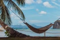 Empty hammock with palm tree and boat on tropical beach. Philippines resort landscape. Idyllic vacation concept.