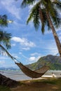 Empty hammock with palm tree and boat on tropical beach. Philippines resort landscape. Idyllic vacation concept. Royalty Free Stock Photo