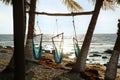 Empty hammocks among palm trees on sandy beach near sea Royalty Free Stock Photo