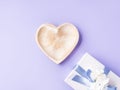 Empty heart shaped dish and gift box on purple. Greeting card