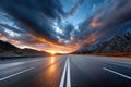 Empty highway at sunset with dramatic clouds and mountains Royalty Free Stock Photo