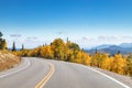 Empty highway winding through a golden fall aspen forest in a Colorado landscape