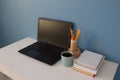 Empty home office of creative entrepreneur with black laptop on white table during lunch break. Modern workspace with blue cup of Royalty Free Stock Photo