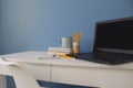 Empty home office of creative entrepreneur with black laptop on white table during lunch break. Modern workspace with blue cup of Royalty Free Stock Photo