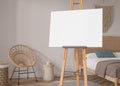 Empty horizontal canvas on wooden easel in modern and cozy room. Mock up interior in scandinavian, boho style. Free