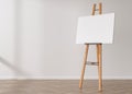 Empty horizontal canvas on wooden easel standing in room. Free, copy space for your picture. Artwork presentation