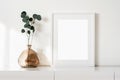 Empty horizontal frame mockup in modern minimalist interior with plant in trendy vase on white wall background.