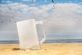 Empty and ice cold beer mug on the beach with seagulls flying Royalty Free Stock Photo