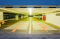 Empty illuminated underground car parking interior under modern mall and arrows on floor