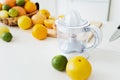 Empty juicer and different citrus fruits on white kitchen table Royalty Free Stock Photo