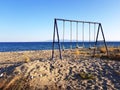 Empty kids swing on a deserted beach Royalty Free Stock Photo