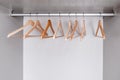 Empty, lacquered light wood clothes hangers hang in wardrobe on metal rod