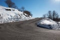 Empty, large mountain road with snow on sides, clear blue sky