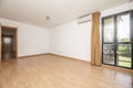 Empty living room of a house with a light brown laminate floor, a bay window with black anodized aluminum windows and light brown Royalty Free Stock Photo