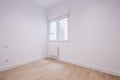 Empty living room of a house with light wood laminate floors, a white aluminum radiator under the window and freshly painted white Royalty Free Stock Photo
