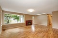 Empty living room interior with brick fireplace and hardwood floor.