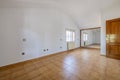 Empty living room with an orange tile floor, plain white walls, a mirrored mural cover, and a double pane window with semi-loft