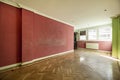 Empty living room with a red painted wall, an oak parquet floor, white