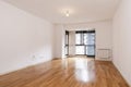 Empty living room with reddish wooden floor and bay window with black anodized aluminum and glass next to an aluminum radiator Royalty Free Stock Photo