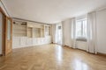 Empty living room with smooth white painted walls, French oak parquet floors laid in a herringbone pattern and custom-made white