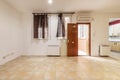 Empty living room with two-tone light brown stoneware floors, electric heat accumulators, windows with curtains and an armored Royalty Free Stock Photo