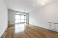 Empty living room with white aluminum radiators and long slat oak parquet flooring