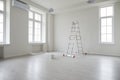 Empty living room with white freshly painted walls, step ladder, and a bucket of paint