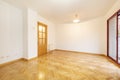 Empty living room with white walls and varnished French oak parquet floor laid in a herringbone pattern and exit to a terrace with