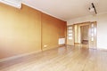 Empty living room with wooden floors, walls painted in various shades of brown, oak double doors with glass and ceiling lamps