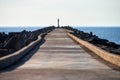 Empty long concrete pier with breakwaters and signal lighthouse in Europe, sea port, copy space Royalty Free Stock Photo