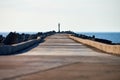 Empty long concrete pier with breakwaters and signal lighthouse in European port, copy space Royalty Free Stock Photo