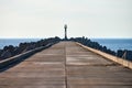 Empty long concrete pier with breakwaters and signal lighthouse in European port, copy space Royalty Free Stock Photo