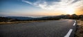 Empty long mountain road to the horizon on a sunny summer day at bright sunset Royalty Free Stock Photo