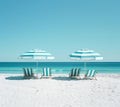 Empty loungers and tents on the white sand beach. Blue sky. Waves in the sea