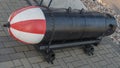 Empty magnetic acoustic aircraft-laid ground mine elongated shape with black body and red-white head mounted with on platform