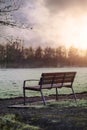 Empty meatal and plastic bench in a park, Green grass field out of focus in the background. Sunset sky with sun flare Royalty Free Stock Photo