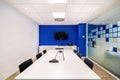 Empty meeting room for conversation with table, chairs, television in modern office interior with blue and white walls. Royalty Free Stock Photo