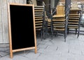 Empty menu board and stacked cafe chairs