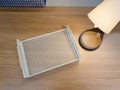 Empty mesh metal paper tray and table lamp on table. Workplace concept