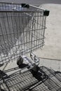 Empty metal shopping cart with shadow outside a supermarket