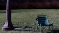 Empty metallic chair near a pillar on a green hill in a park on a sunny day