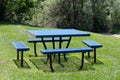 Empty metallic outdoor picnic table with benches on grass lawn.