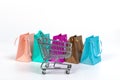 Empty mini shopping cart and colourful paper bags isolated on bright background, mockup for design Royalty Free Stock Photo