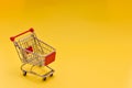 An empty mini supermarket cart on a yellow background. Royalty Free Stock Photo