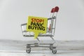 An empty miniature shopping cart with a yellow speech bubble written with advice of Stop! panic buying in reflect to current
