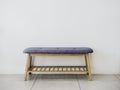 Empty minimal style wooden bench with blue fabric pad and wooden slatted shelf.