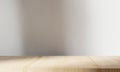 Empty minimal wooden table with shadow drop on white wall