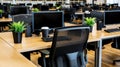 Empty modern office desks, computers, plants, coffee; workday preparation Royalty Free Stock Photo