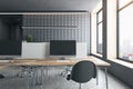 An empty modern office interior with desks, computers, and a chair in a room with large windows and a city view, conveying a Royalty Free Stock Photo