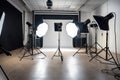 Empty modern studio with pro equipment. Brightly illuminated room with black background. Camera equipment, chair, reflector setup Royalty Free Stock Photo